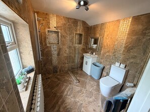 A bathroom with a shower, sink, toilet, and a window with plants. - Blissful Retreat - 4 Bedroomed House (Bridgend)
