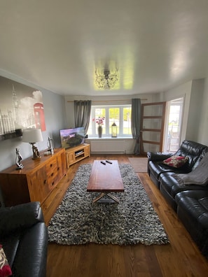 A living room with a wooden cabinet, a television, a sofa, and a coffee table. - Blissful Retreat - 4 Bedroomed House (Bridgend)