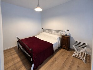 A bedroom with a single bed, a bedside table, a hanging light fixture, and a drying rack. - DELIGHTFUL INDEPENDENT LOFT IN ALPI ARENA WITH FREE PRIVATE PARKING (Torino)