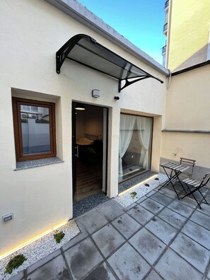 A building with a covered entrance, a window with a curtain, and a small outdoor seating area. - DELIGHTFUL INDEPENDENT LOFT IN ALPI ARENA WITH FREE PRIVATE PARKING (Torino)