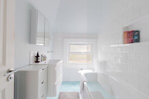 Un baño moderno con un lavamanos blanco, un espejo y una ventana.