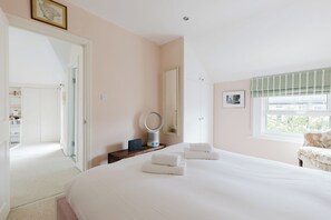 Un dormitorio con una cama grande, una mesita de noche con lámpara, un espejo, un armario y una ventana con persianas.