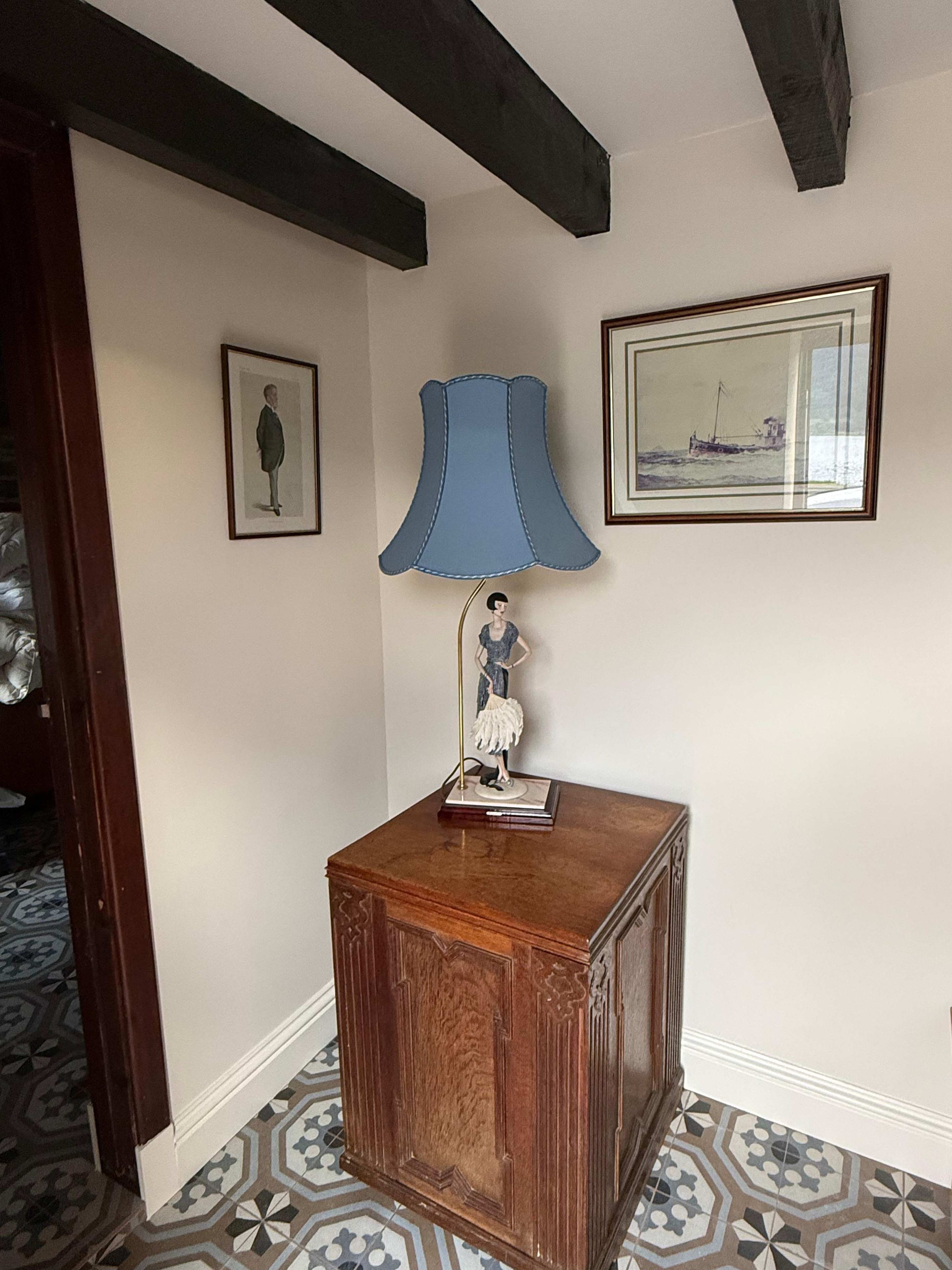 Une pièce avec un meuble en bois, une lampe bleue et deux tableaux encadrés accrochés au mur.