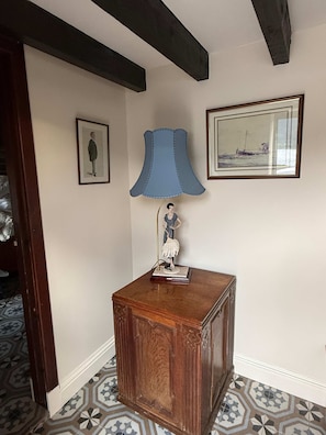 Quarto com armário de madeira, abajur azul e duas fotos emolduradas na parede.