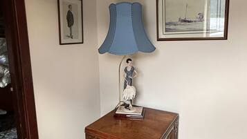 A room with a wooden cabinet, a blue lamp, and two framed pictures on the wall.