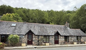 Une petite maison en pierre avec un toit en pente, une porte en bois et une petite fenêtre.