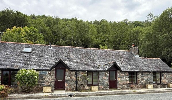 A stone cottage with a sloped roof, a wooden door, and a small window. - Stone Cottage, Glencoe, Pet friendly (Glencoe)