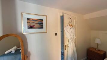 Une chambre d’hôtel avec un lit, une table de chevet avec une lampe, un tableau encadré au mur et un peignoir accroché à la porte.
