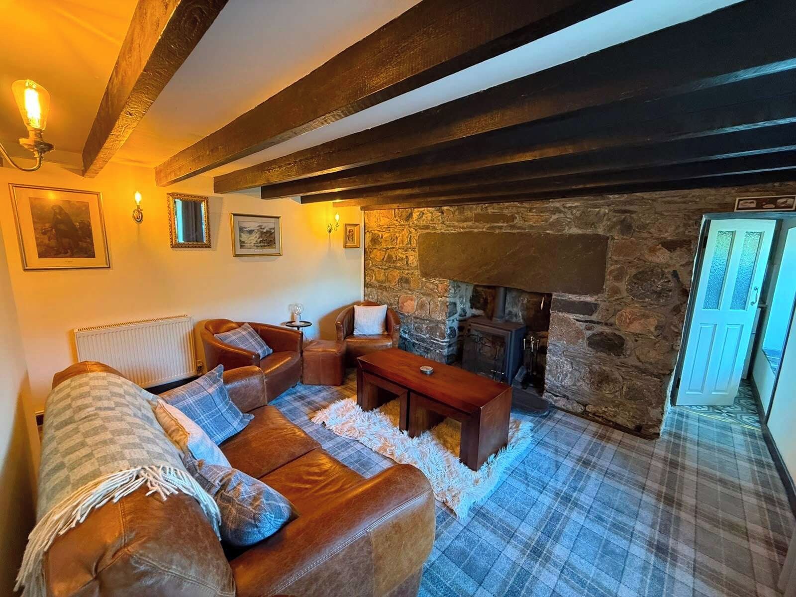 A cozy living room with a fireplace, leather sofas, and a stone wall.