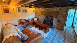 A cozy living room with a fireplace, leather sofas, and a stone wall. - Stone Cottage, Glencoe, Pet friendly (Glencoe)