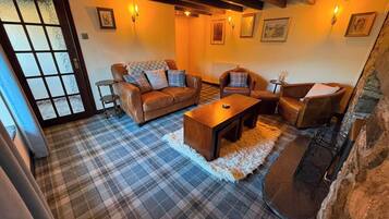 A cozy living room with a sofa, armchairs, a coffee table, and a fireplace.