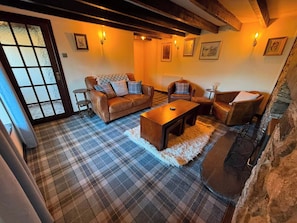 A cozy living room with a sofa, armchairs, a coffee table, and a fireplace. - Stone Cottage, Glencoe, Pet friendly (Glencoe)