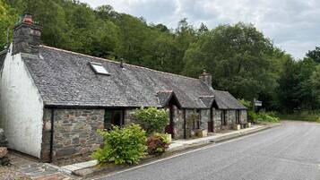 A row of stone cottages with a gravel driveway and a sign indicating a car park.