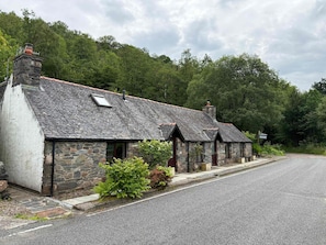 A row of stone cottages with a gravel driveway and a sign indicating a car park.