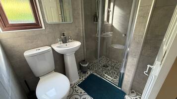 A bathroom with a toilet, sink, and glass-enclosed shower.
