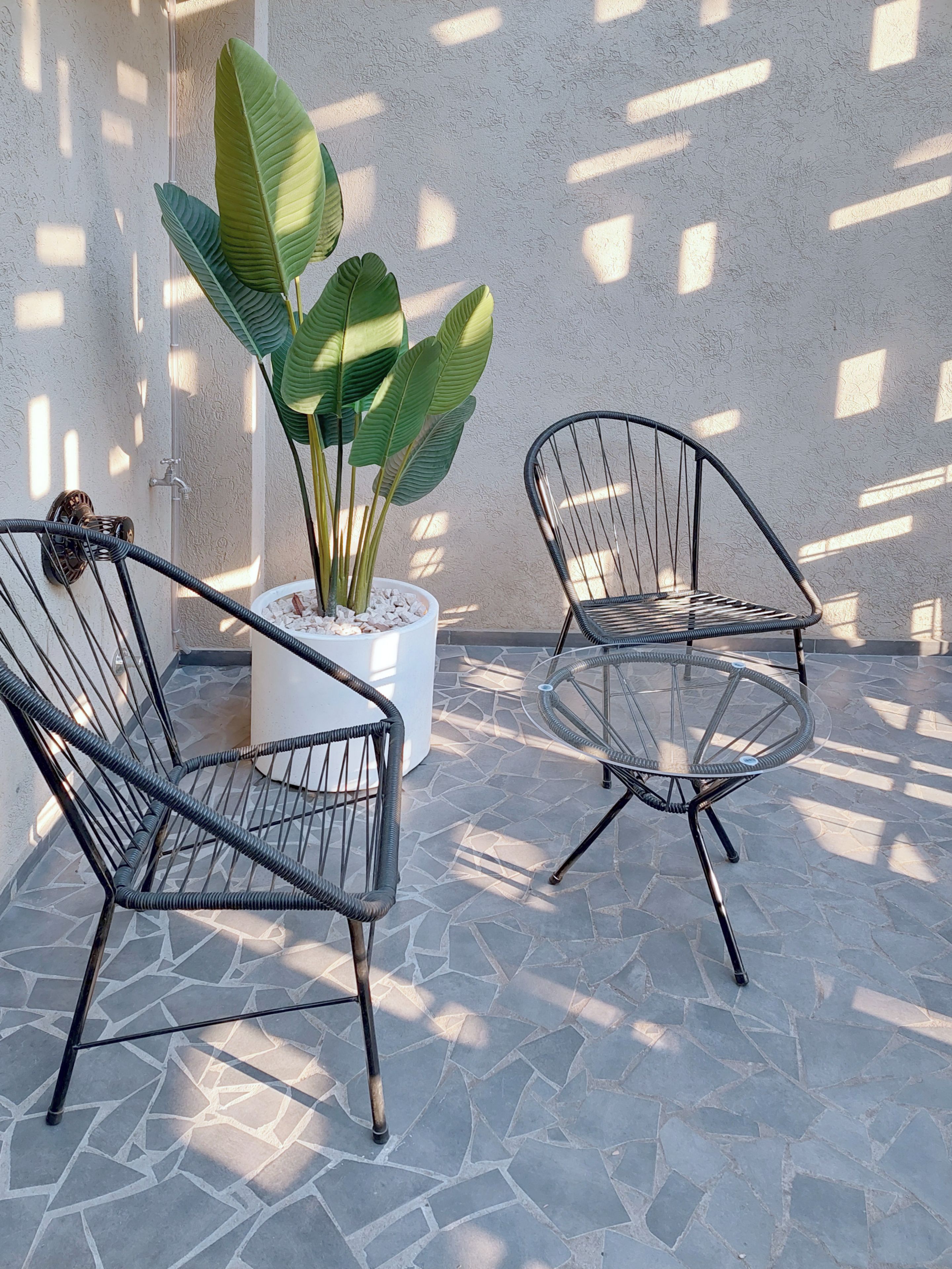 Two metal-framed chairs and a potted plant on a tiled patio.
