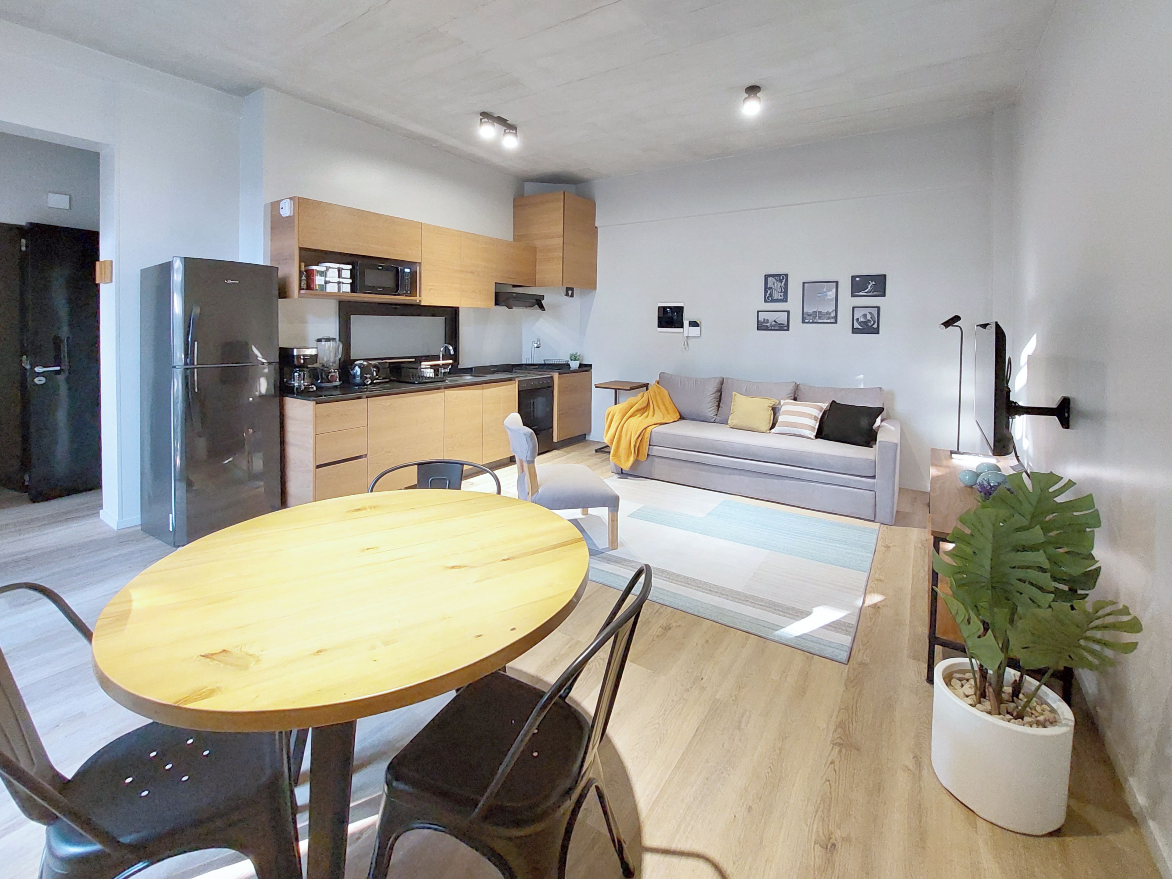 Una cocina moderna con refrigerador, microondas y estufa. Hay una mesa de comedor con sillas y un sofá en la sala.