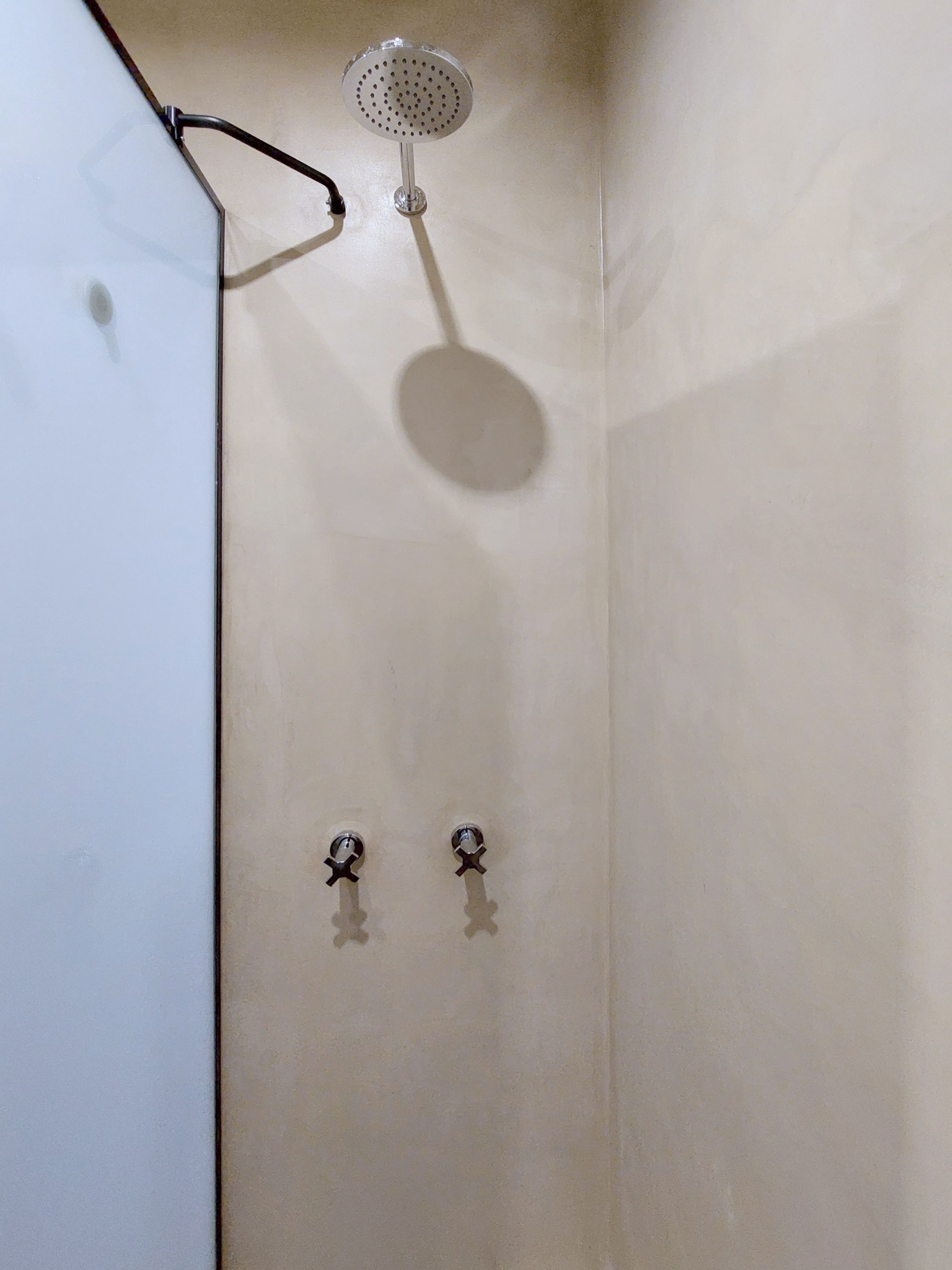 Una ducha con cabezal de ducha de mano y dos mandos de pared.