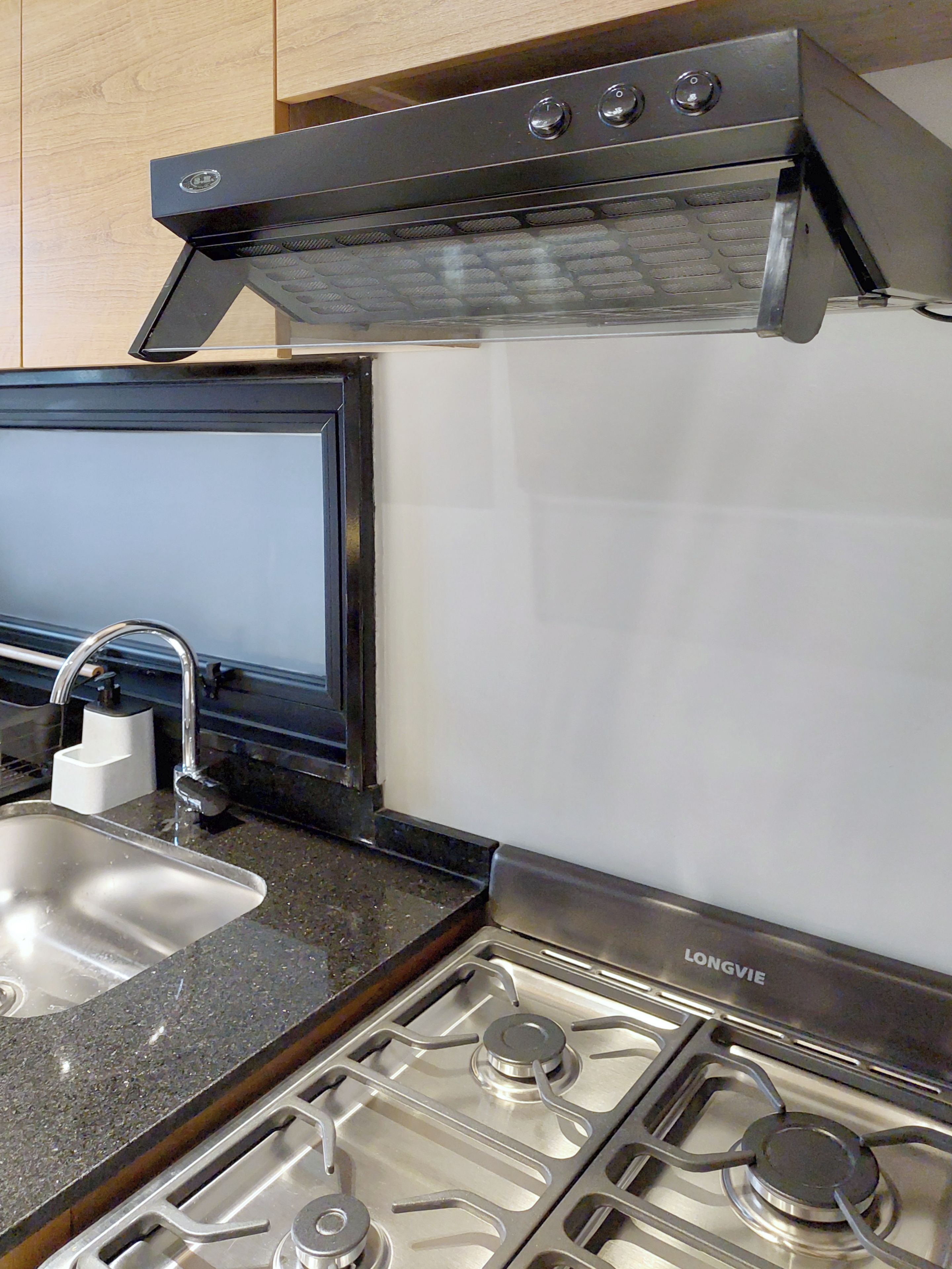A kitchen with a stainless steel stove, a sink, and a range hood.