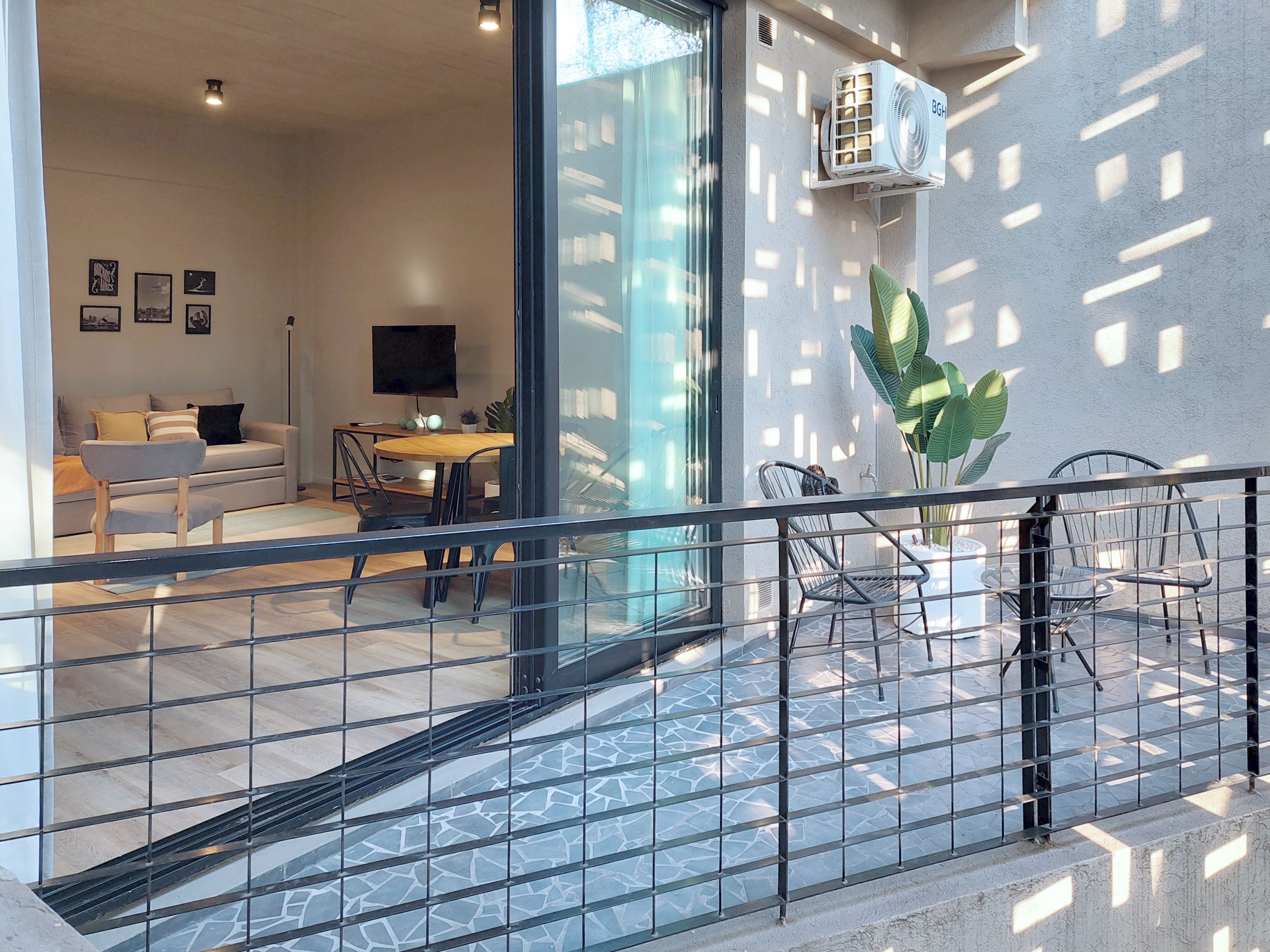 Een modern interieur met een eethoek, een bank, een televisie en een balkon met een hekwerk.