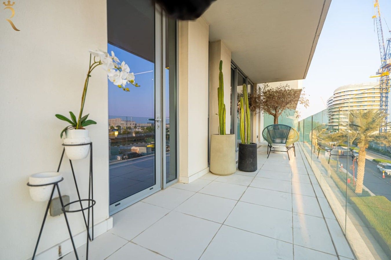 Un balcon agrémenté de plantes en pot, d’une chaise et offrant une vue sur le paysage urbain.