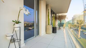 Un balcon agrémenté de plantes en pot, d’une chaise et offrant une vue sur le paysage urbain.