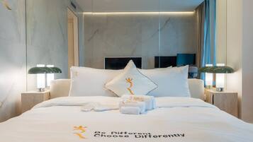 A hotel room with a bed, pillows, a nightstand, and a wall-mounted TV.