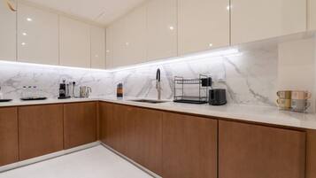 A modern kitchen with marble countertops, wooden cabinets, and a built-in sink.