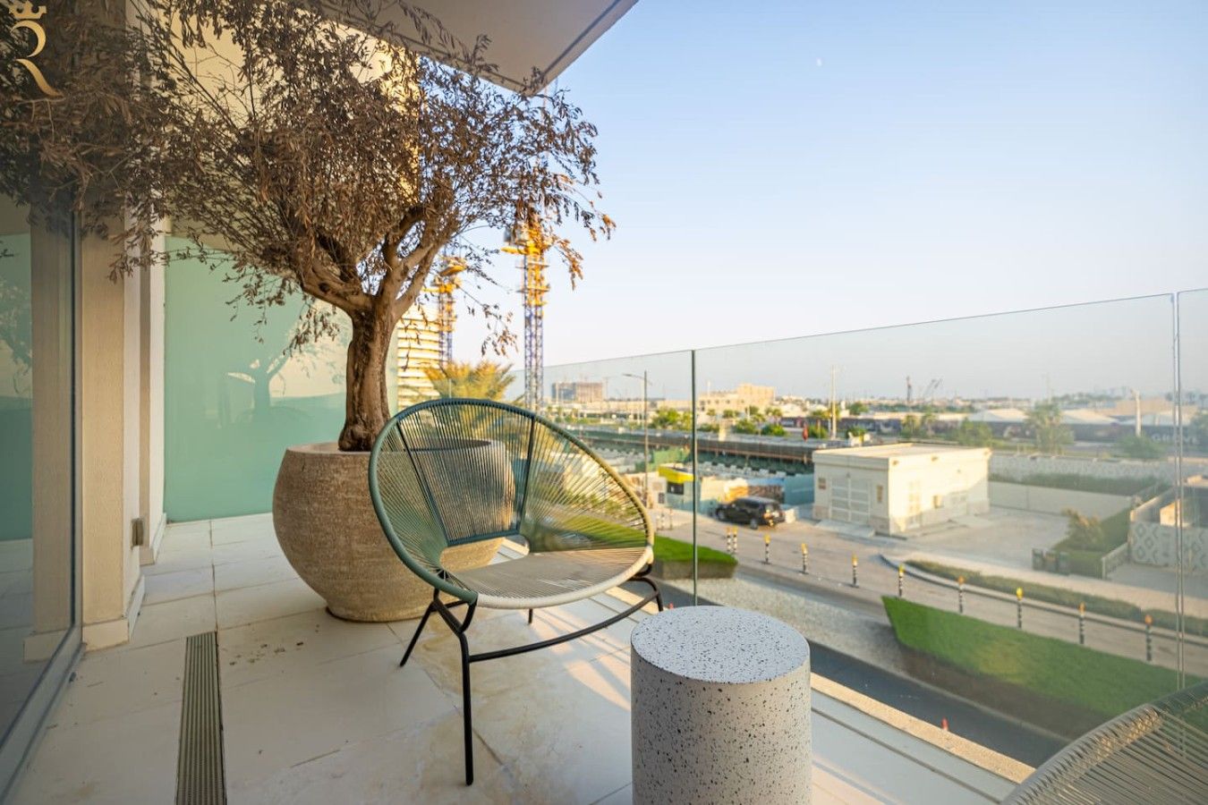 Ein Balkon mit einem Sessel, einem Blumentopf mit einem Baum und freiem Blick auf die Stadtlandschaft.