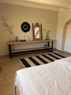 Ein Schlafzimmer mit einem Bett, einer Bank, einem Spiegel und Wanddekorationen.