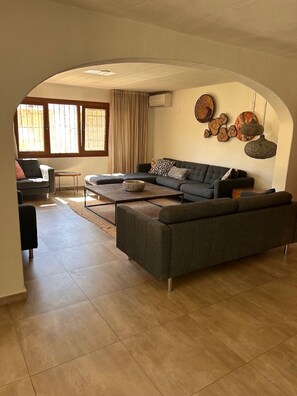 Ein Wohnzimmer mit einer Eckcouch, einem Couchtisch und einem Essbereich mit Tisch und Stühlen.