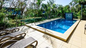 A swimming pool with tiled flooring and lounge chairs.