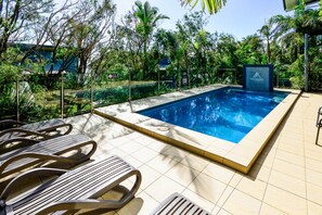 Una piscina amb paviment de rajoles i gandules.