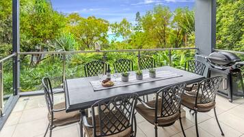 An outdoor dining area with a table, chairs, and a grill.