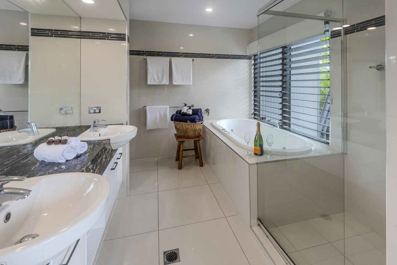 Une salle de bain moderne avec deux lavabos, une grande baignoire et une douche à parois de verre.