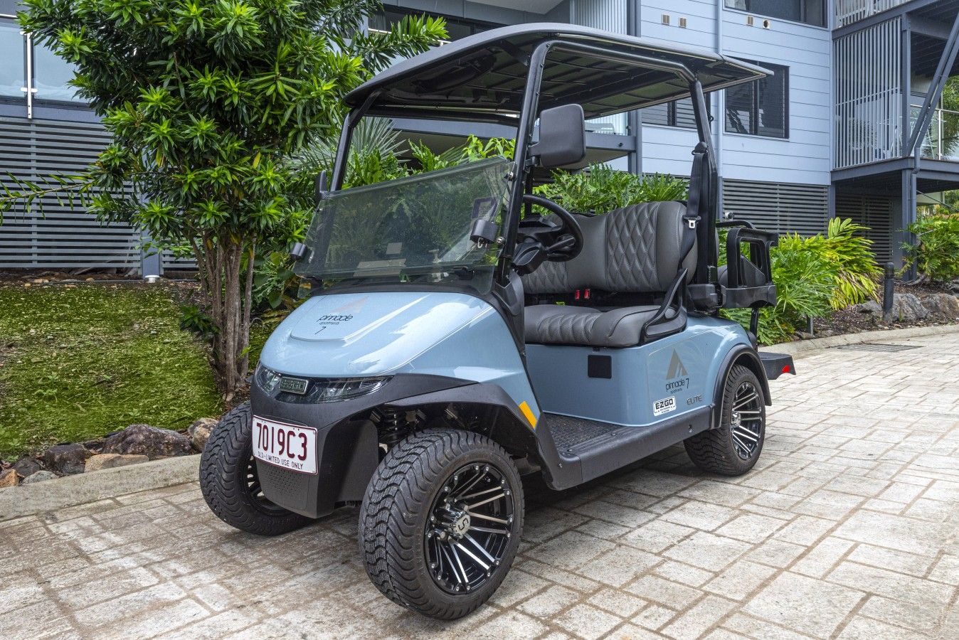 A golf cart parked on a paved area with a building in the background.