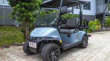 A golf cart parked on a paved area with a building in the background.