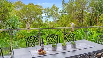 An outdoor dining area with a table set for two, surrounded by lush greenery and trees.