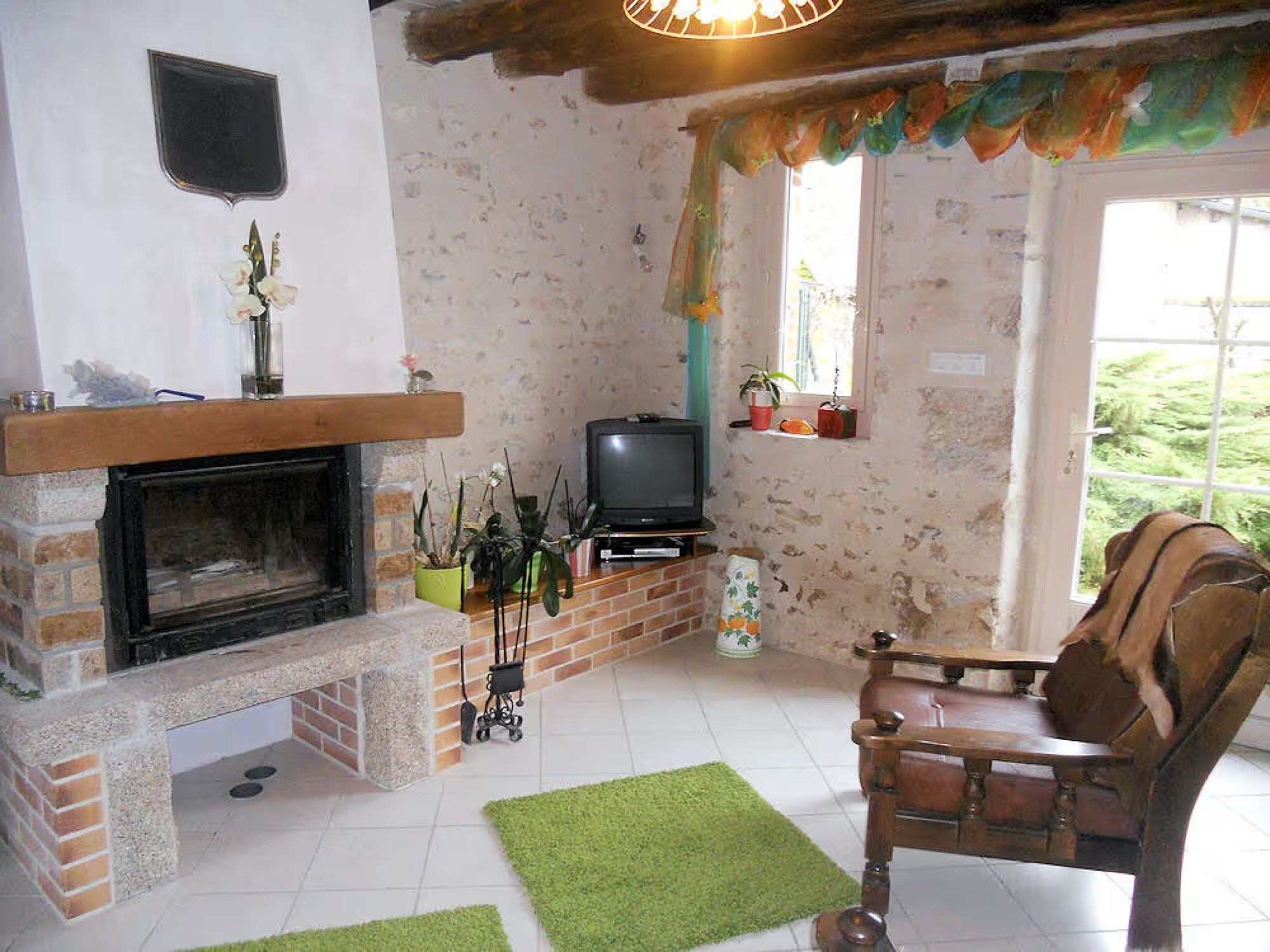 A cozy living room with a fireplace, a television, and a comfortable chair.
