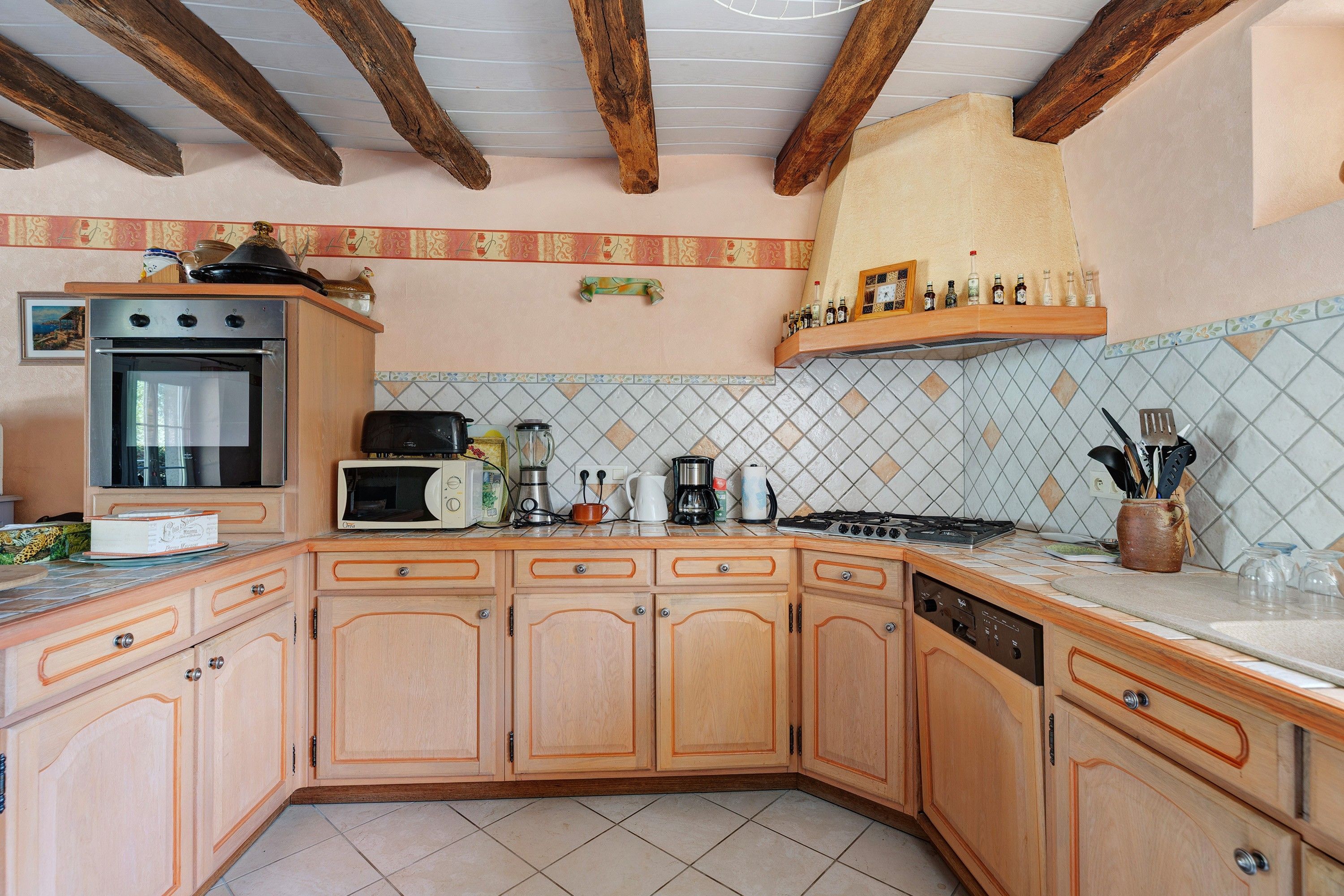 Una cocina con armarios de madera, microondas, estufa y diversos electrodomésticos.