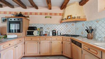 Una cocina con armarios de madera, microondas, estufa y diversos electrodomésticos.