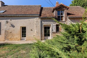 A rustic building with a tiled roof, a small window, and a door.