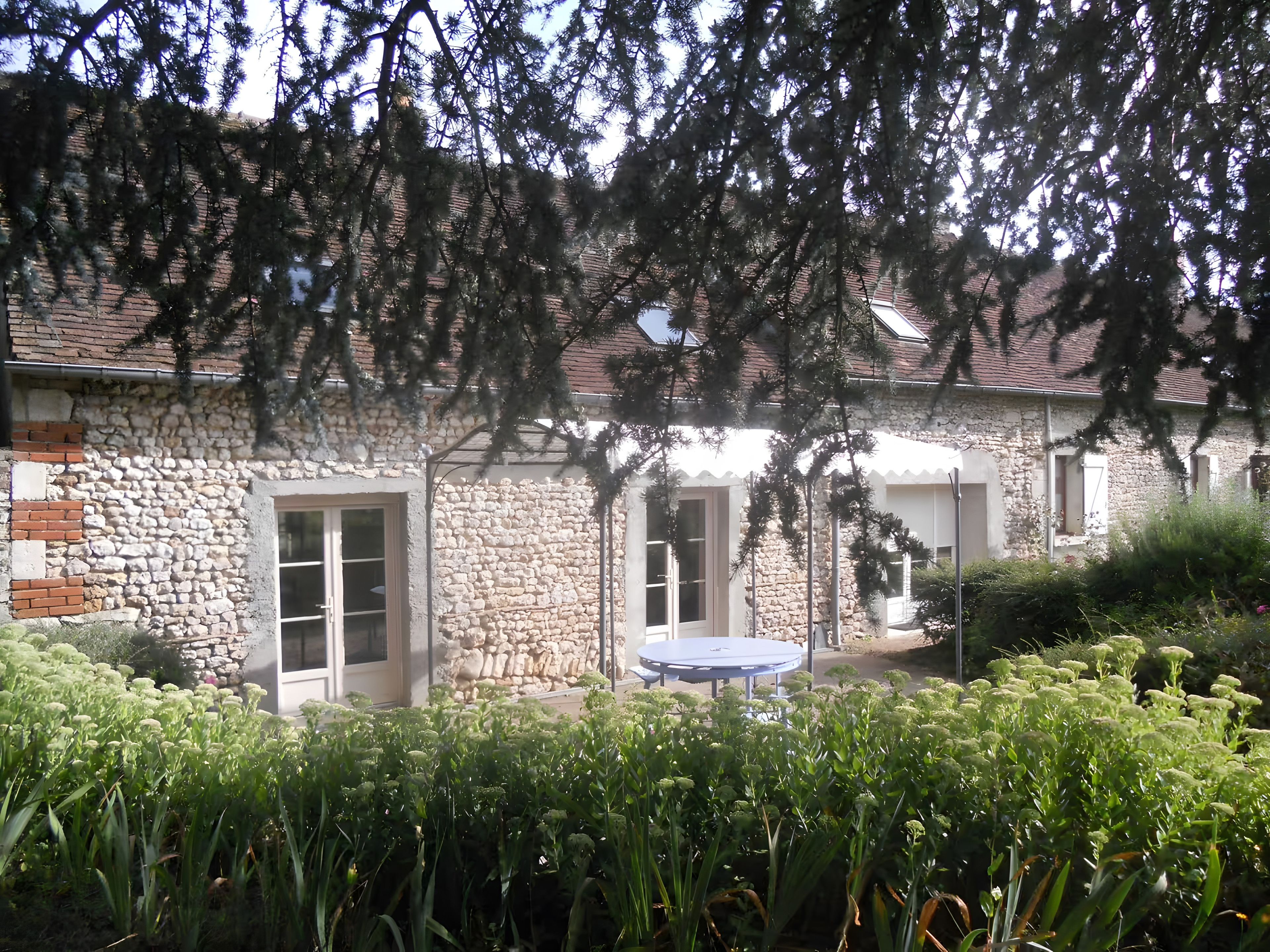 A stone building with a round table and chairs in the yard.