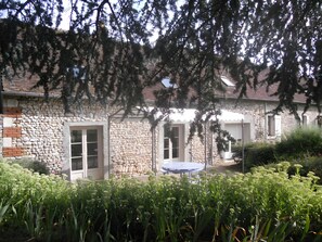 A stone building with a round table and chairs in the yard.