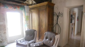 Quarto com duas poltronas de couro, um armário de madeira e um suporte de metal decorativo.