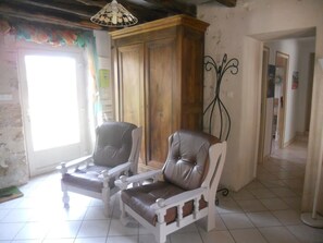 A room with two leather armchairs, a wooden cabinet, and a decorative metal stand.