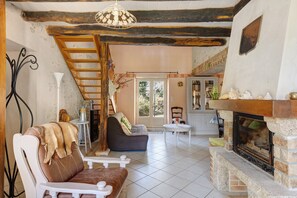 A cozy living room with a fireplace, a sofa, a dining table, and a staircase.