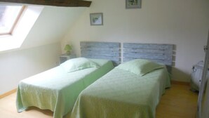 Quarto com duas camas, um claraboia e um vigamento de madeira.