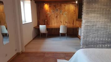 A room with a wooden ceiling, a desk with two chairs, a large window, and a wall with decorative moon shapes.