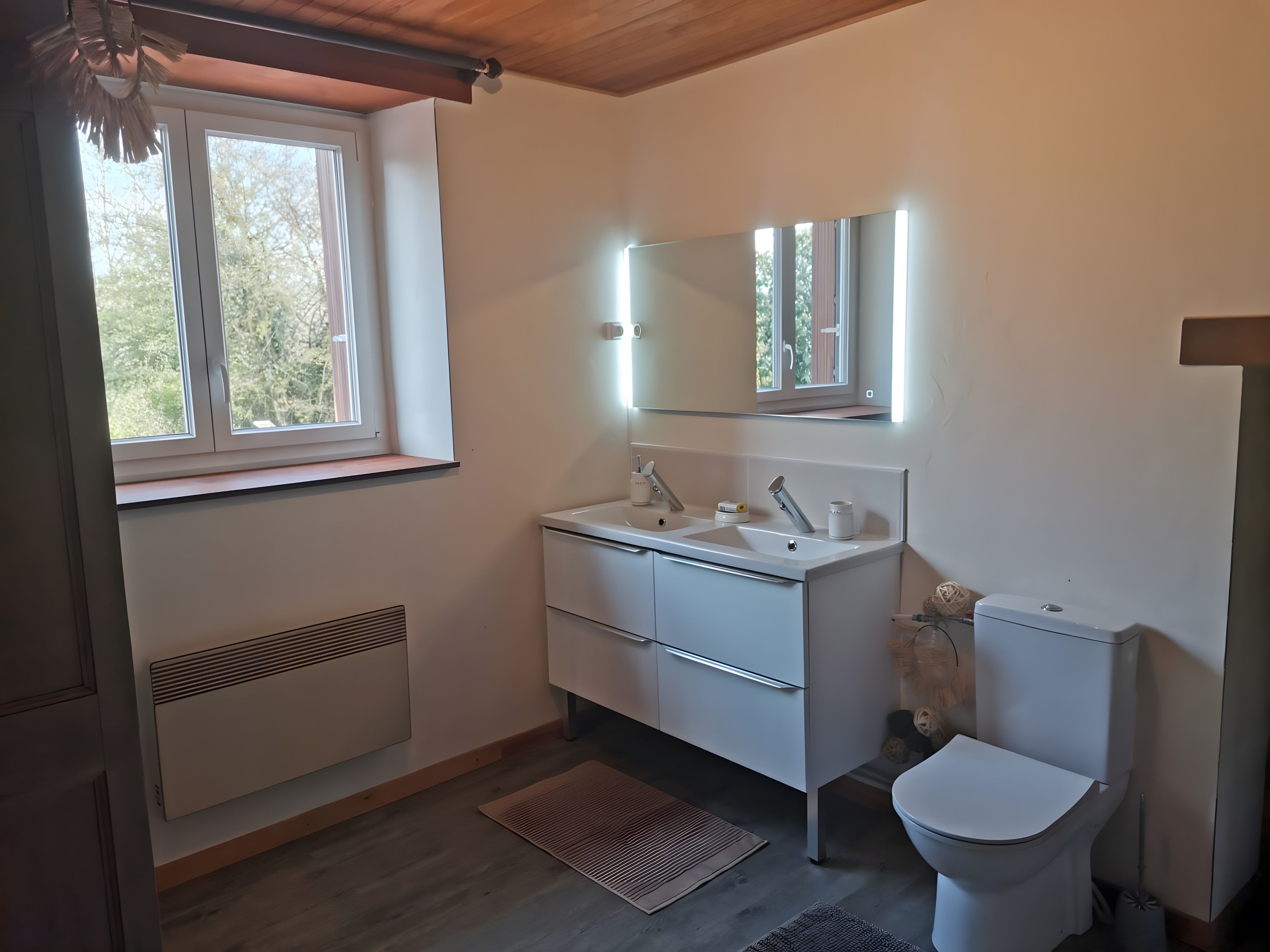 Een moderne badkamer met een wit wastafelmeubel, spiegel en toilet.
